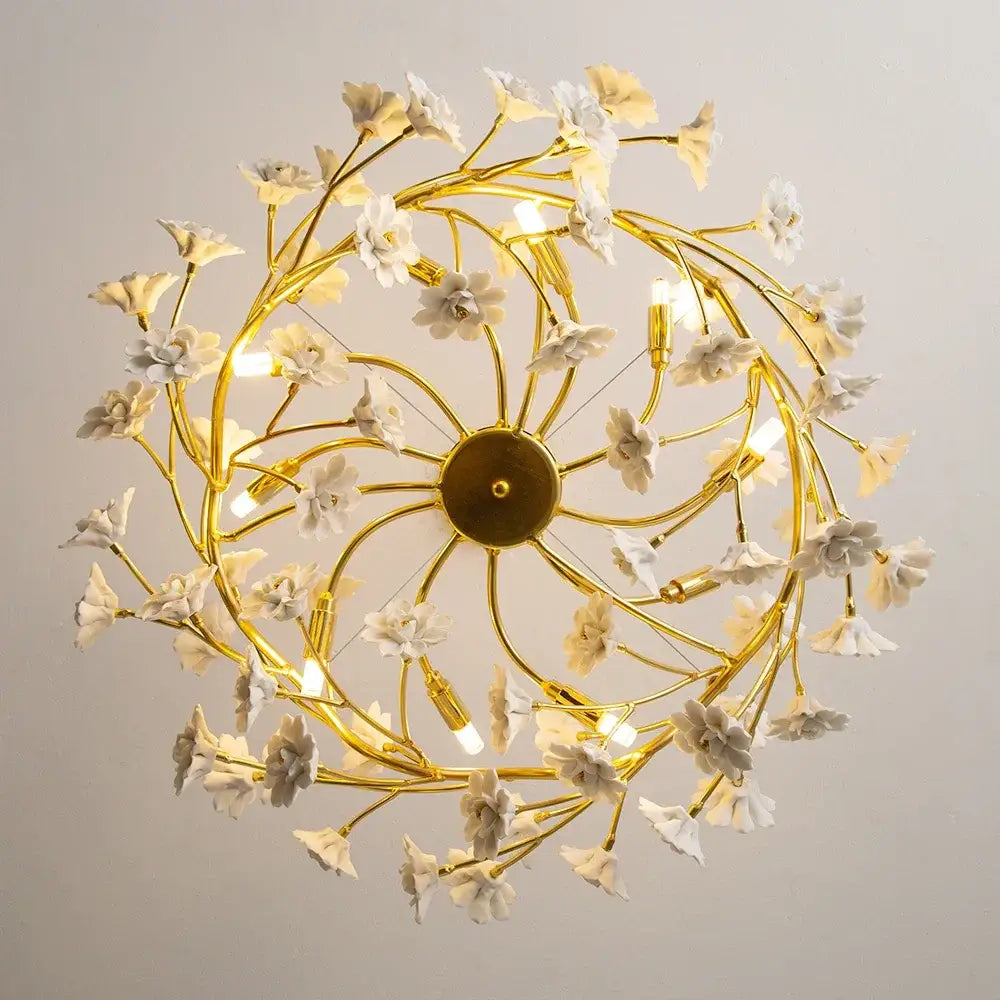 Golden chandelier featuring delicate french white flower ceramic accents and slender metallic branches for romantic decor