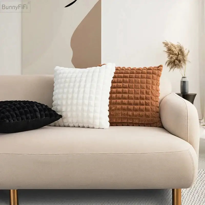 Cream-colored sofa with gold-tone legs featuring decorbites fluffy faux fur cushion cover in cream and brown tones