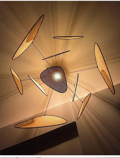 A modern french design rattan chandelier with a black perforated disc and golden-brown woven panels for home lighting