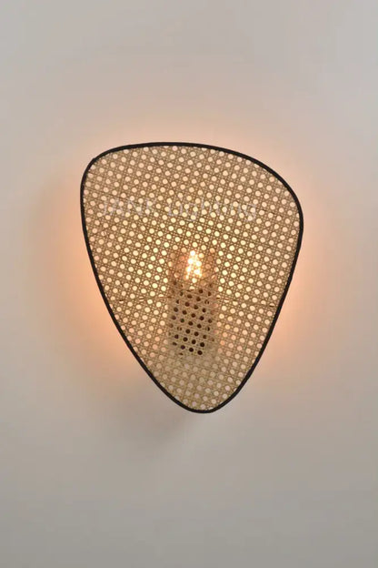 A warm-toned teardrop-shaped wall sconce with woven rattan shade and black trim in french design rattan chandelier style