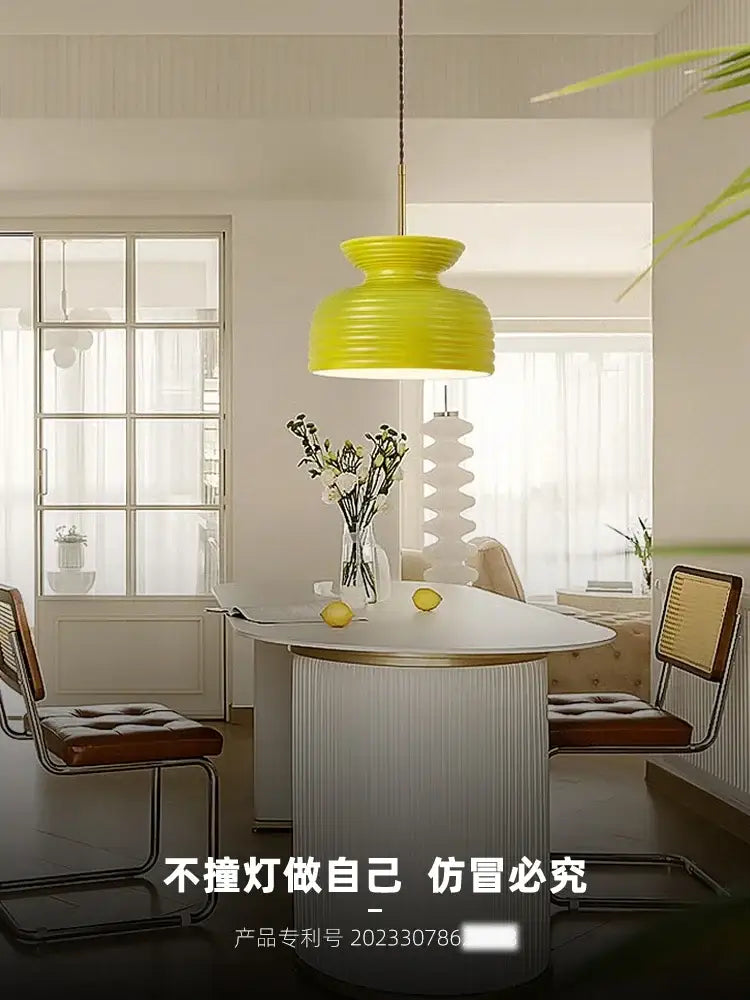 Vibrant yellow decorbites french minimalist pendant lamp with ribbed texture hanging above a modern dining table