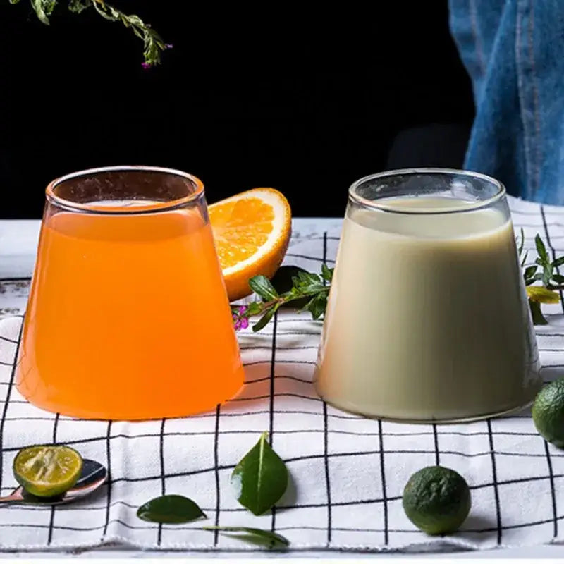 Two clear glass tumblers from decorbites fuji mountain glass drinkware set filled with orange and creamy beige beverages