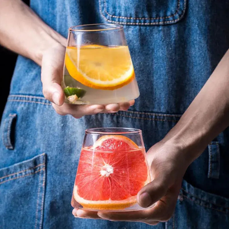 Two clear stemless glass drinkware tumblers with a modern tapered design from decorbites fuji mountain glass set held in hands