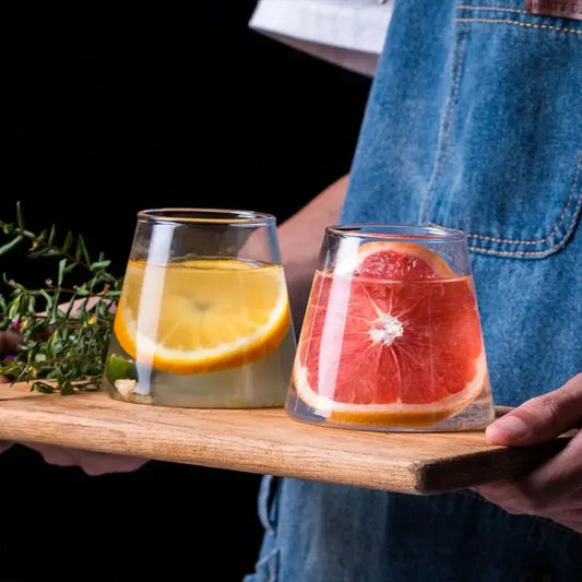 Two clear glass drinkware tumblers from decorbites fuji mountain glass set with lemon and grapefruit slices on wood board