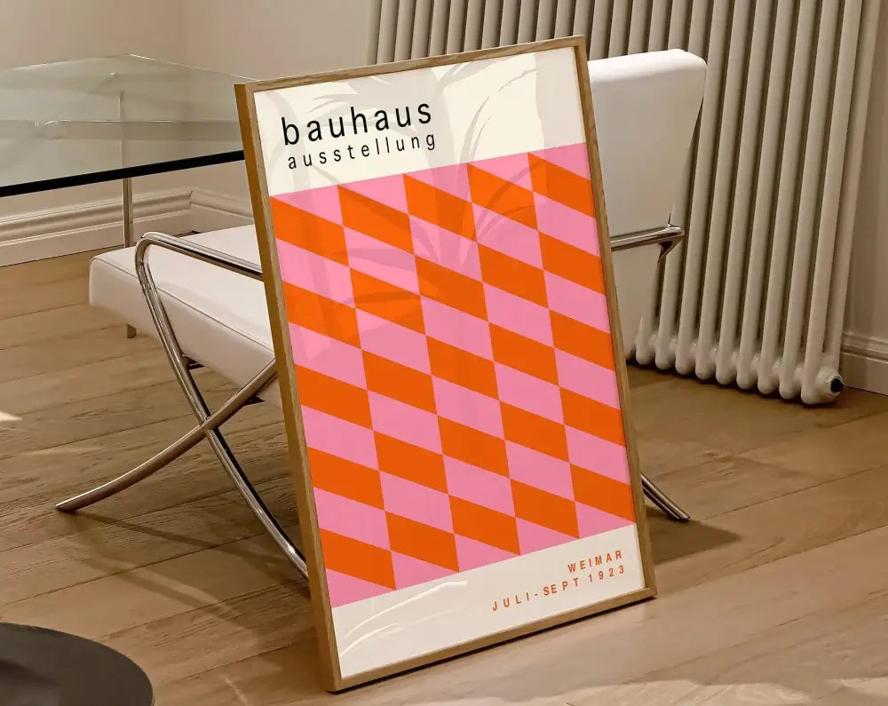 A framed geometric bauhaus canvas poster with bold orange and pink diamond pattern in a light wood frame