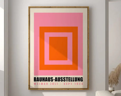 Framed geometric bauhaus canvas print featuring concentric pink and orange squares with black bauhaus text on cream mat