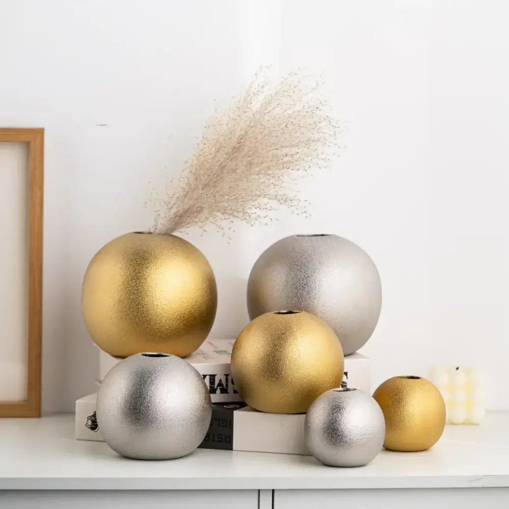 Set of decorbites geometric gold and silver spherical ceramic vases with dried pampas grass on white surface