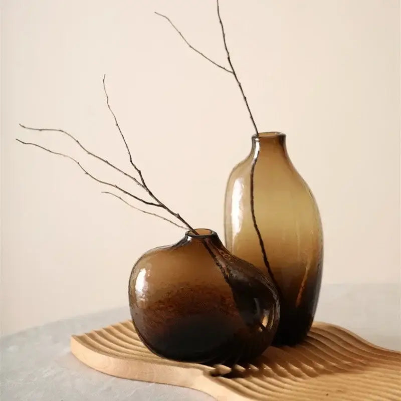 Two amber-tinted glass vases with a smooth rounded design for single flower arrangement from DecorBites geometric zen glass collection
