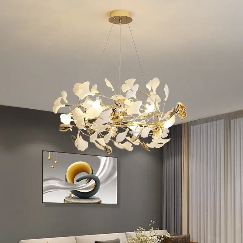 Gold-toned decorbites ginkgo leaf chandelier with delicate white leaf-shaped shades suspended from brass fixture