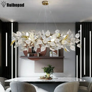 A modern decorbites ginkgo leaf crystal chandelier with silver and gold glass leaves on a brass fixture for dining room
