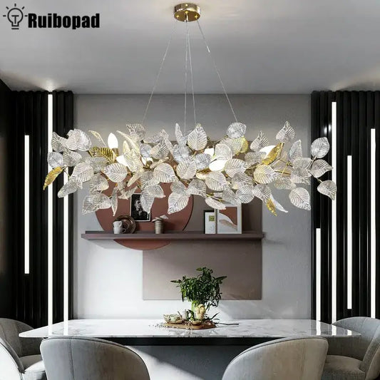 A modern decorbites ginkgo leaf crystal chandelier with silver and gold glass leaves on a brass fixture for dining room