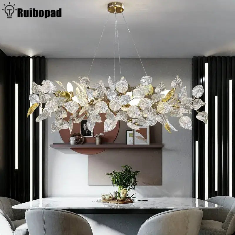 A modern decorbites ginkgo leaf crystal chandelier with silver and gold glass leaves on a brass fixture for dining room