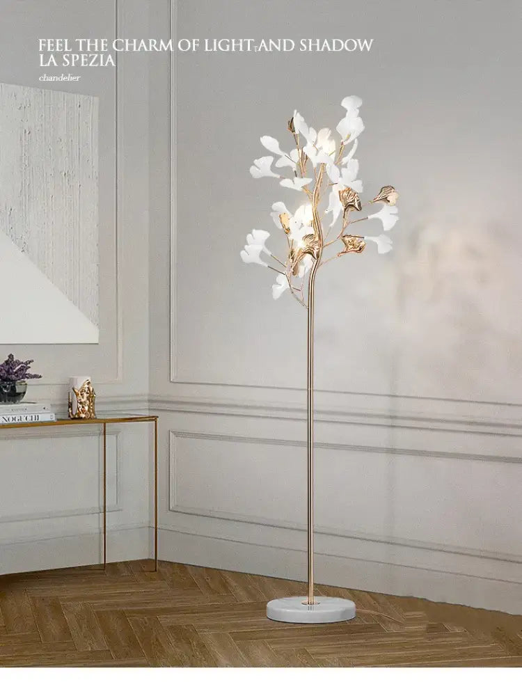 Elegant gold-toned decorbites ginkgo leaf floor lamp with white and metallic flower shades on polished marble base