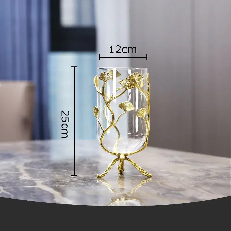 A clear glass vase with a golden ginkgo leaf glass frame and ornate legs for modern desk decoration by DecorBites™