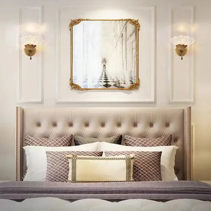 Gold-framed rectangular mirror with ornate detailing above tufted headboard featuring decorbites ginkgo leaf wall lights
