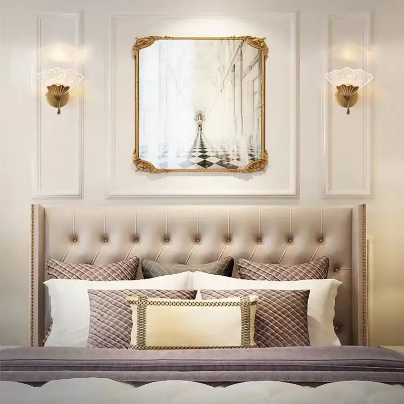 Gold-framed rectangular mirror with ornate detailing above tufted headboard featuring decorbites ginkgo leaf wall lights