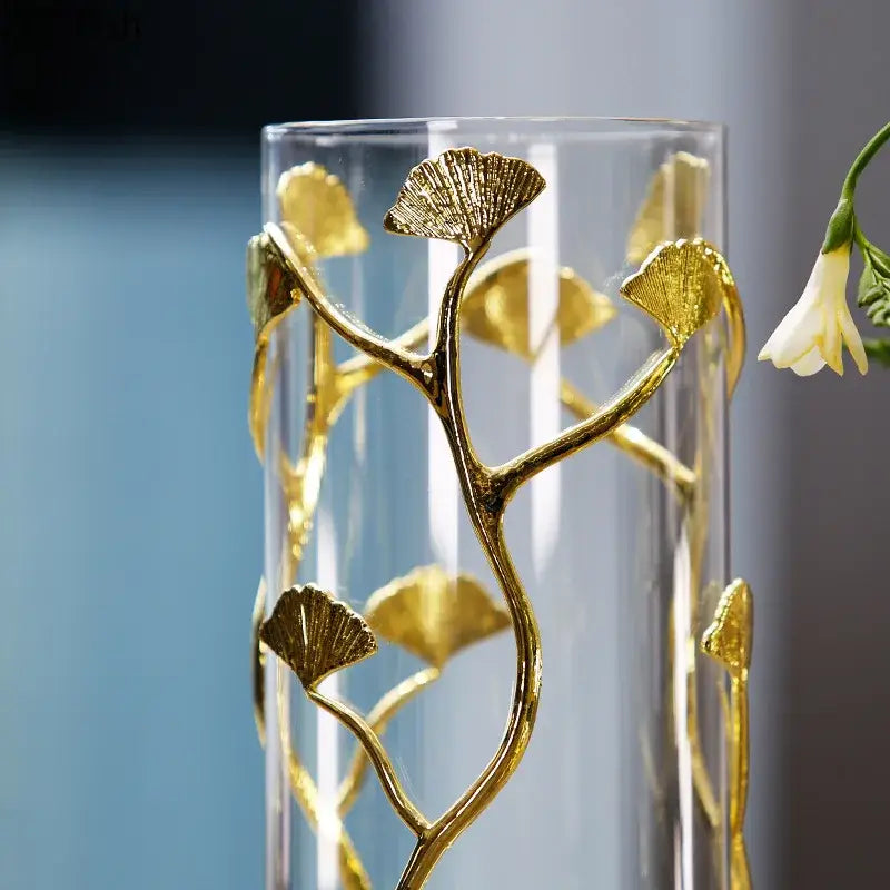 A clear glass decorbites ginkgo leaf metal flower stand vase with gold-toned ginkgo leaf embellishments