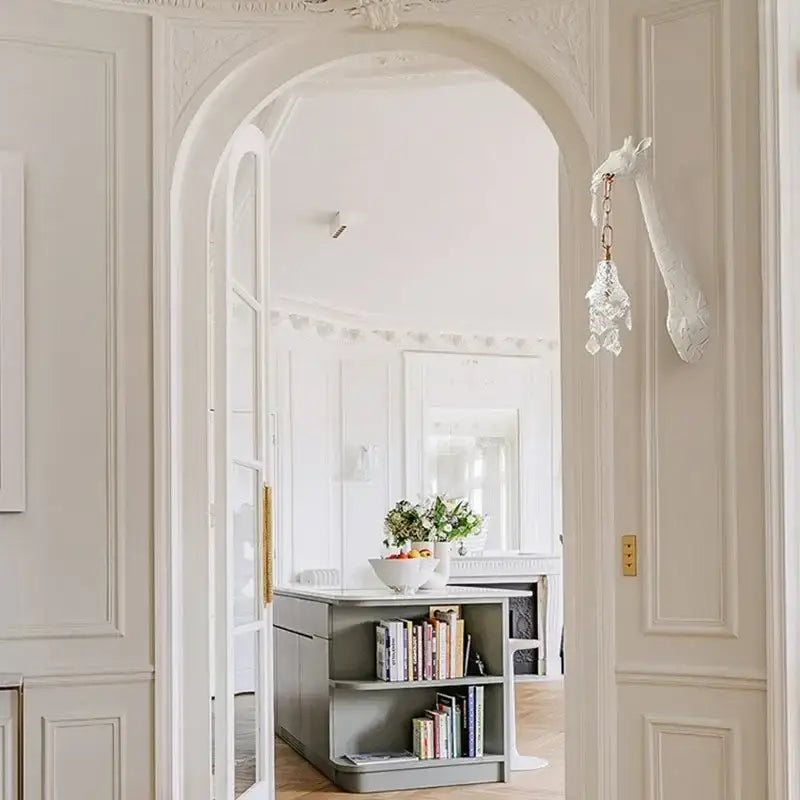 A delicate white crystal chandelier hangs from an ornate archway in DecorBites giraffe love wall lamp design