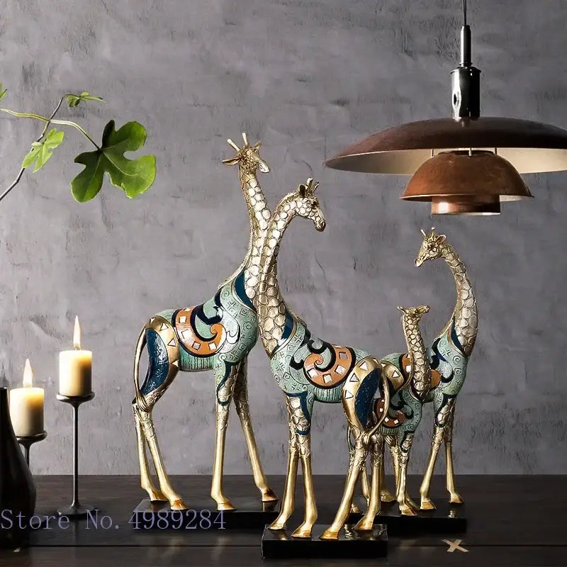 Three ornate decorbites giraffe mother and child painted sculptures with gold-toned legs and teal blue orange patterns on black bases