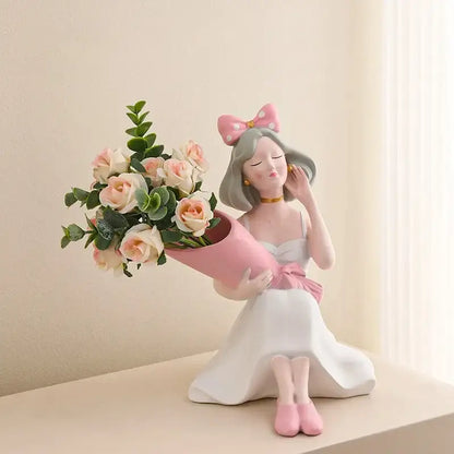 A pink and white resin decorbites girl statues vase ornament of a seated girl holding roses for office decor