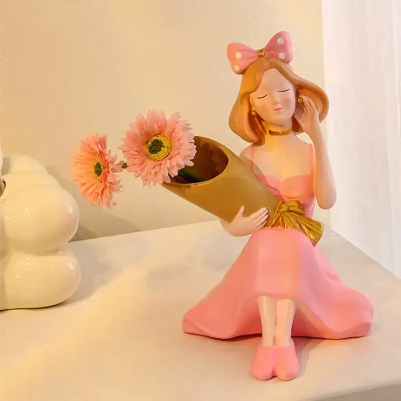 Pink resin decorbites girl statues with polka-dot bow holding golden vase and pink daisies for office decor
