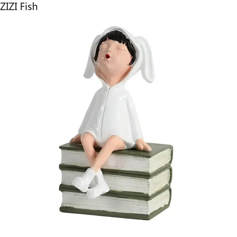 White resin sculpture figure of a child in bunny pajamas yawning on stacked books for modern decor