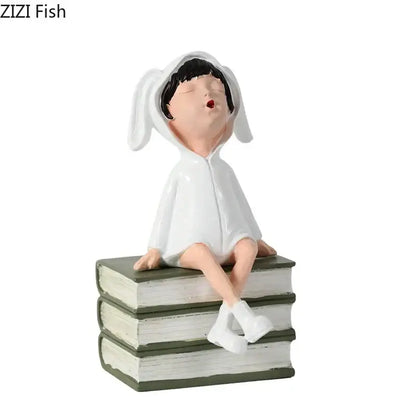 White bunny-eared resin sculpture figure sitting atop stacked books in DecorBites™ modern girls and books decor