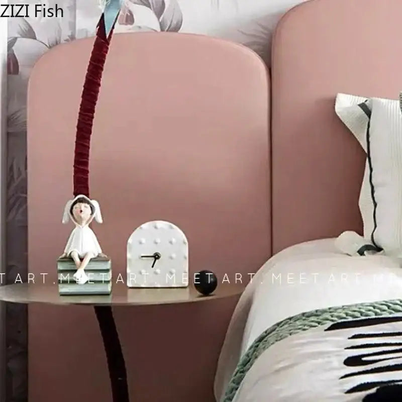 A delicate white resin sculpture figure of a seated girl with bunny ears on stacked books for modern decor