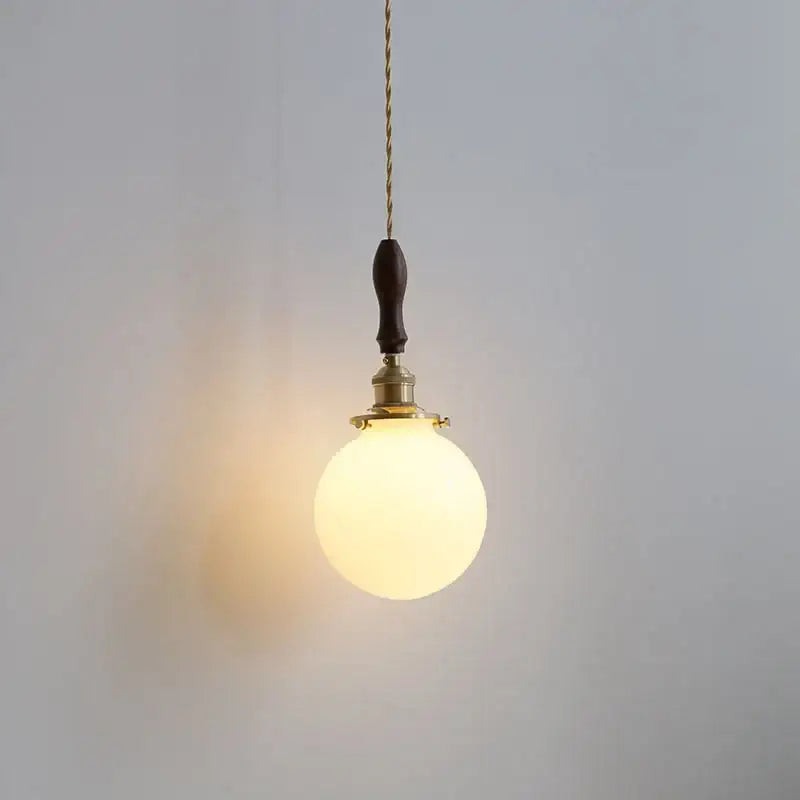 Warm-toned spherical glass pendant lamp with brass fixture and dark wood toggle switch by DecorBites Glabe LED