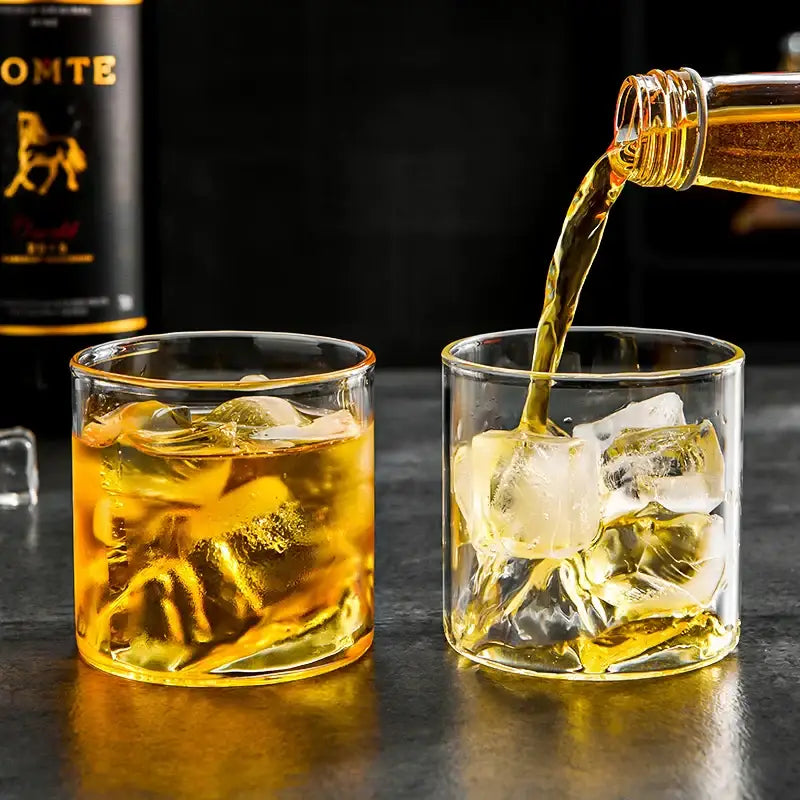 Golden amber whiskey pours into a clear double-walled decorbites glacier wine cup with Fuji artwork and ice cubes