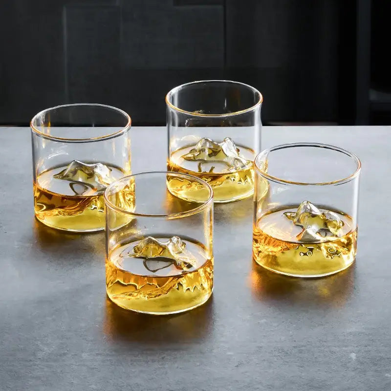 Four clear glass decorbites glacier wine cups with gold-rimmed edges filled with amber whisky and ice cubes