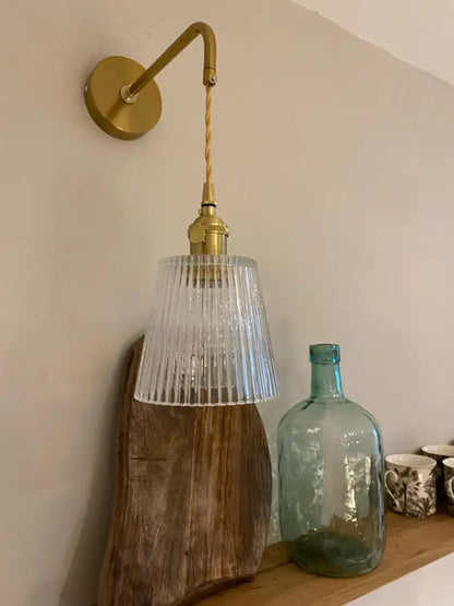 A brass decorbites glass adjustable led wall light with ribbed clear glass shade and twisted cord for bedroom decor