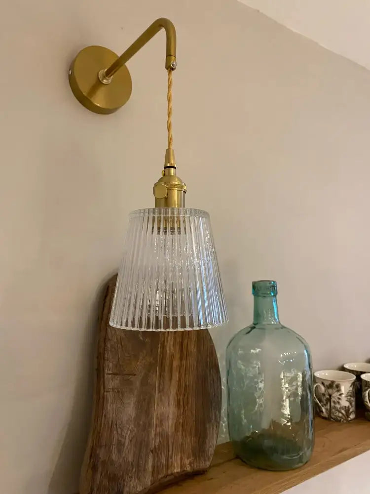 A brass decorbites glass adjustable led wall light with ribbed clear glass shade and twisted cord for bedroom decor