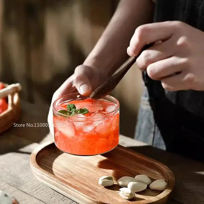 A decorbites glass afternoon tea dessert bowl filled with vibrant orange beverage ice and fresh mint leaves