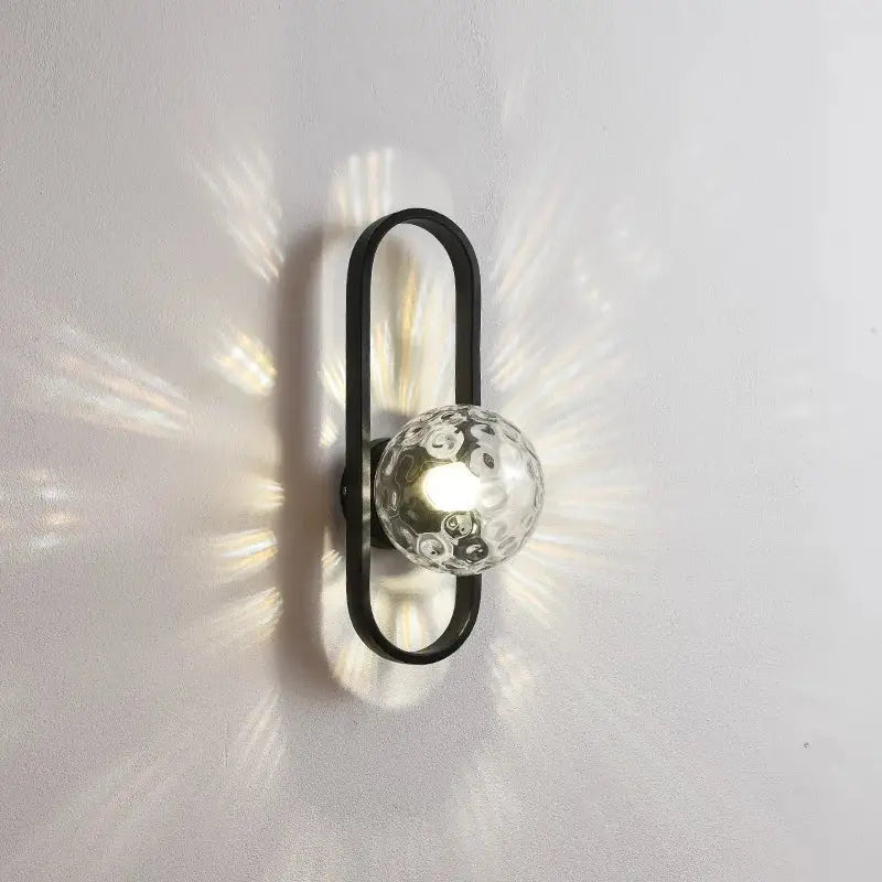 Black metal wall lamp decorbites glass aisle with textured clear glass globe emitting warm indoor light