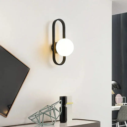 Black metal DecorBites glass aisle wall lamp with sleek curved frame and round frosted glass bulb for indoor decoration