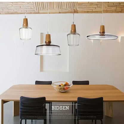 Decorbites glass and wood pendant light with clear glass and wooden accents hanging above a dining table