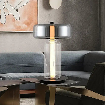 Modern desk lamp with chrome-finished top and clear glass body emitting warm light from decorbites glass art desk design