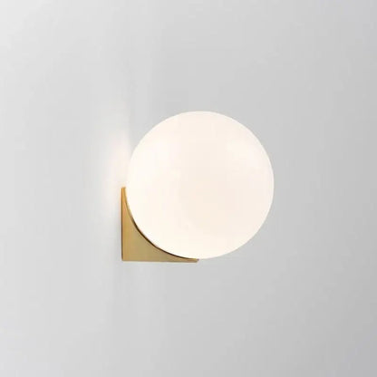 A sleek decorbites glass ball wall lamp with frosted white glass shade and polished brass base for bedroom decor