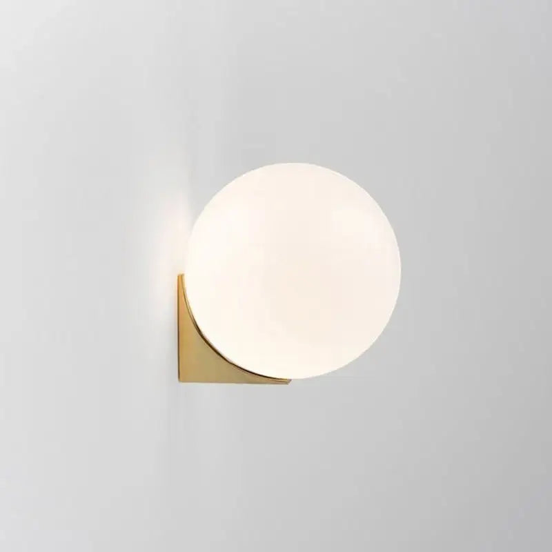 A sleek decorbites glass ball wall lamp with frosted white glass shade and polished brass base for bedroom decor