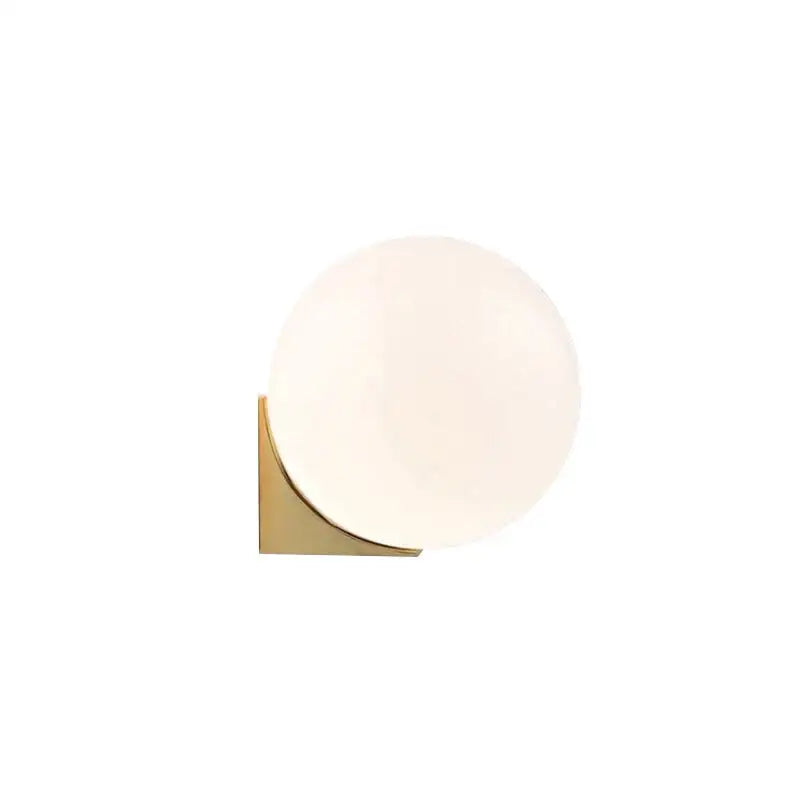 A sleek decorbites glass ball wall lamp with frosted glass globe and polished brass base for bedroom lighting