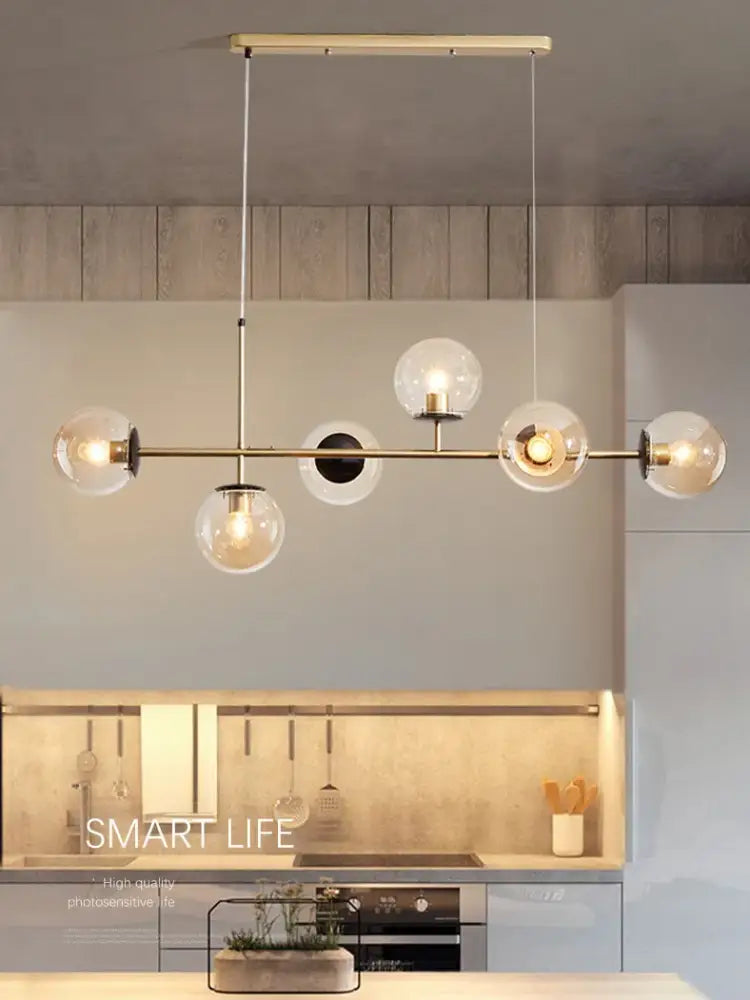 Modern brass decorbites glass ball ceiling chandelier with clear glass globe shades and black accents for kitchen dining room