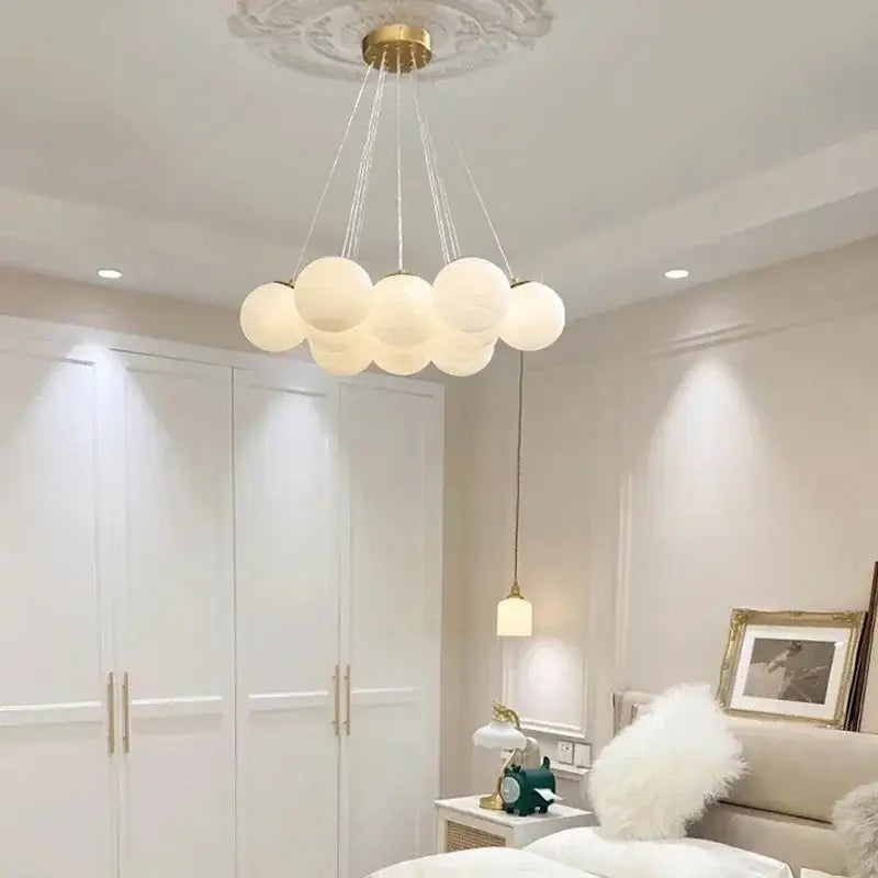 White spherical glass ball ceiling pendant light with gold-toned fixture and delicate cords by decorbites
