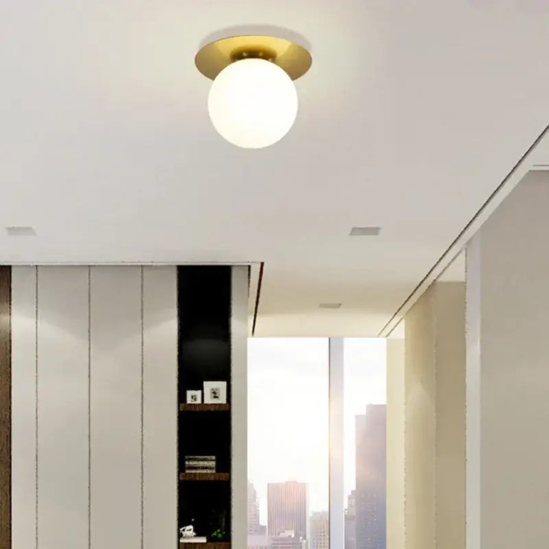 A modern decorbites glass ball ceiling light with polished brass base and frosted glass globe for bedroom hallway stairs