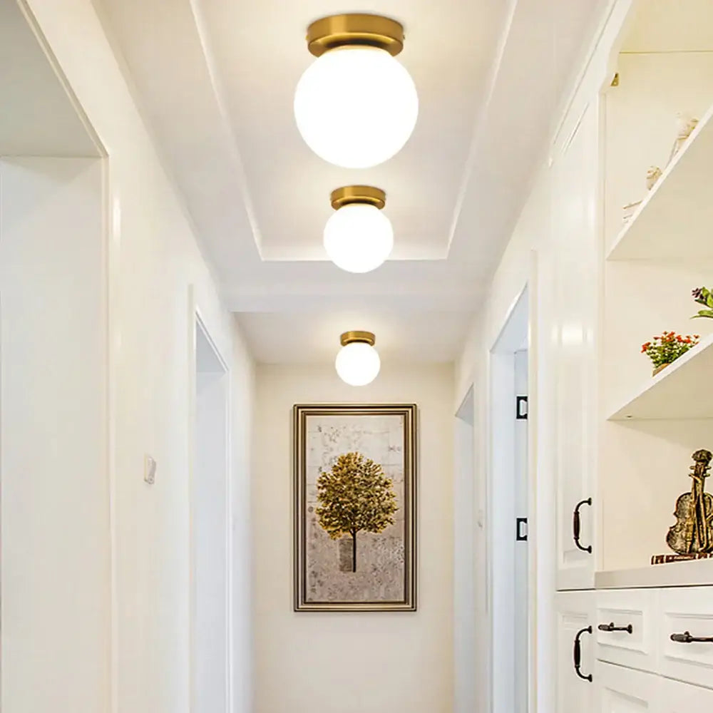 Three frosted glass globe ceiling lights with brass fixtures mounted in a row for modern bedroom decorbites glass ball ceilings