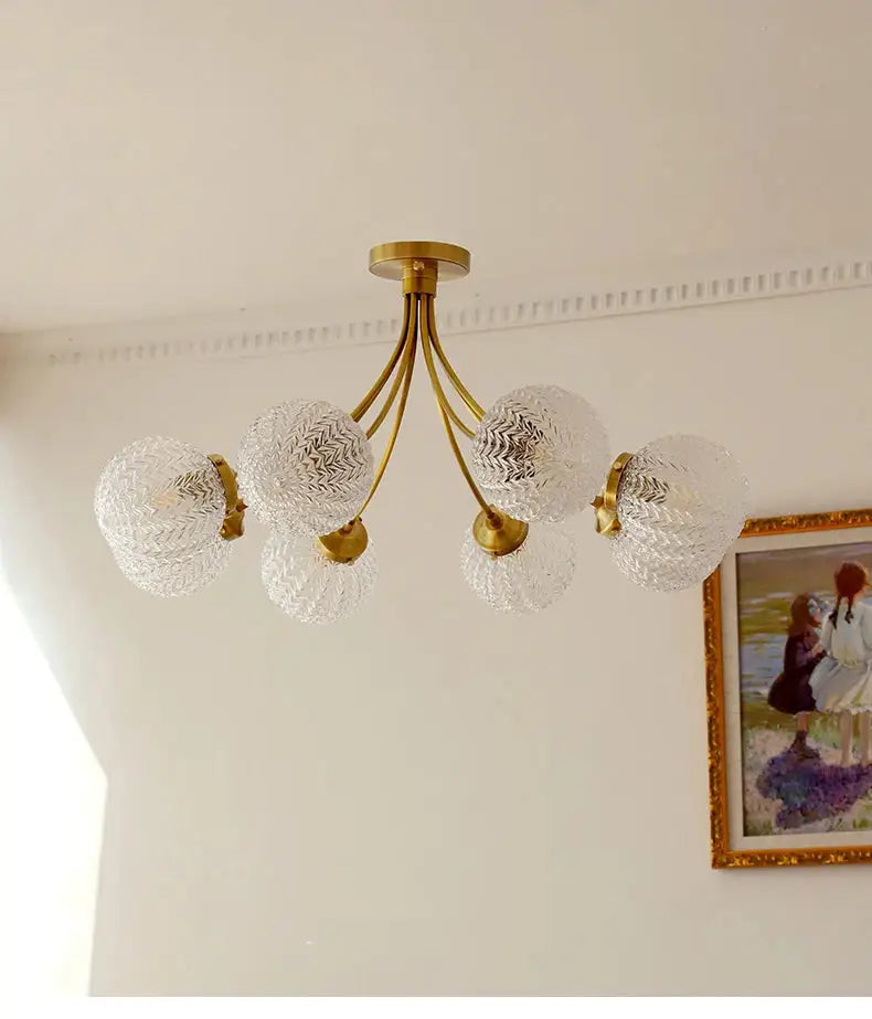 A brass decorbites glass ball ceiling light with five clear textured glass globe shades for modern living spaces