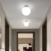 Two round white decorbites glass ball ceiling lights with sleek metallic bases illuminate a modern hallway