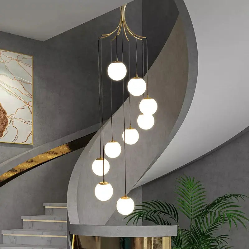 Modern gold-toned decorbites glass ball chandelier with seven white glass globes suspended by black cords for dining room