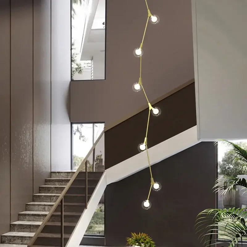 A modern gold-toned decorbites glass ball chandelier with spherical bulbs on a curved wire for villa hotel decor