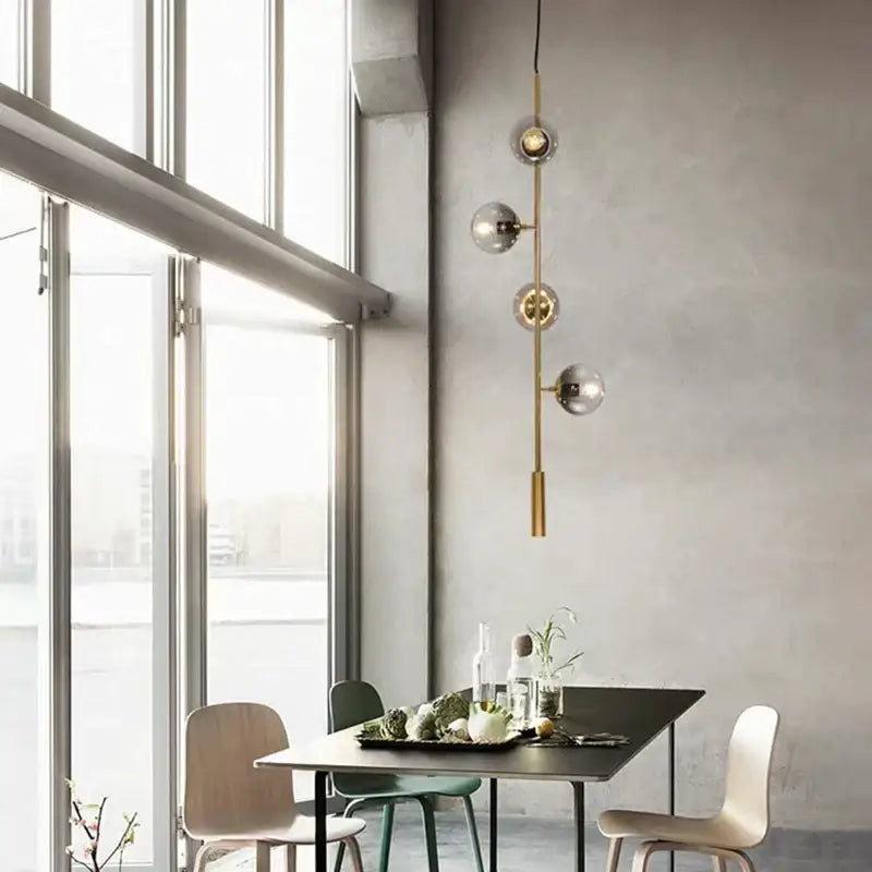 A modern brass decorbites glass ball chandelier with four spherical glass globes for kitchen and bar lighting